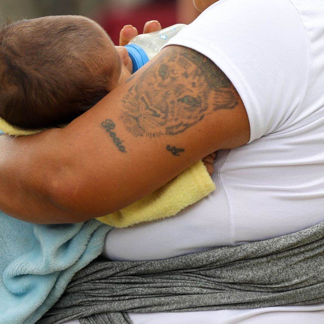Bebé es sostenido en brazos por sus padres